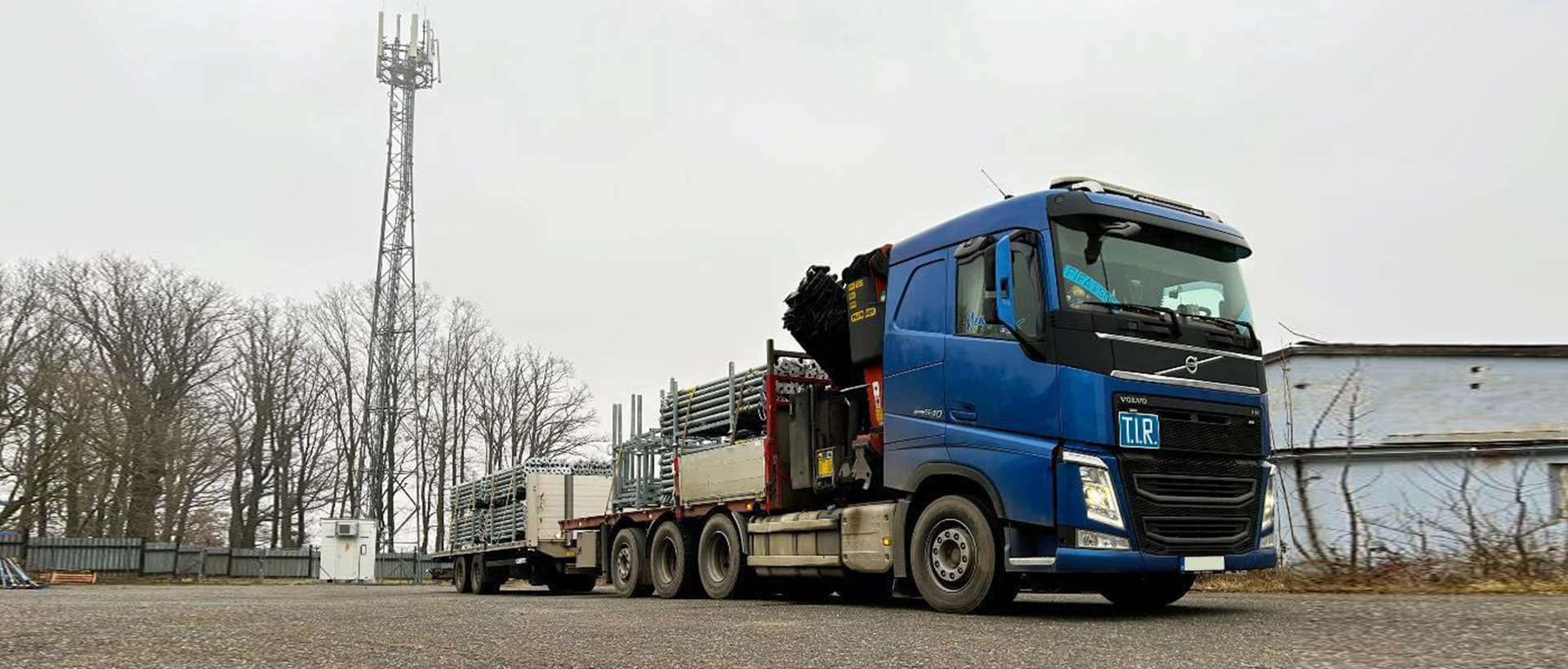 Nákladní vozidlo Volvo s hydraulickou rukou a vlekem naloženým materiálem